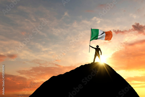 Irish flag being waved at the top of a mountain summit. 3D Rendering