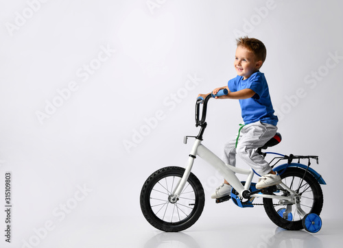 young boy happily riding on a bicycle on isolated background