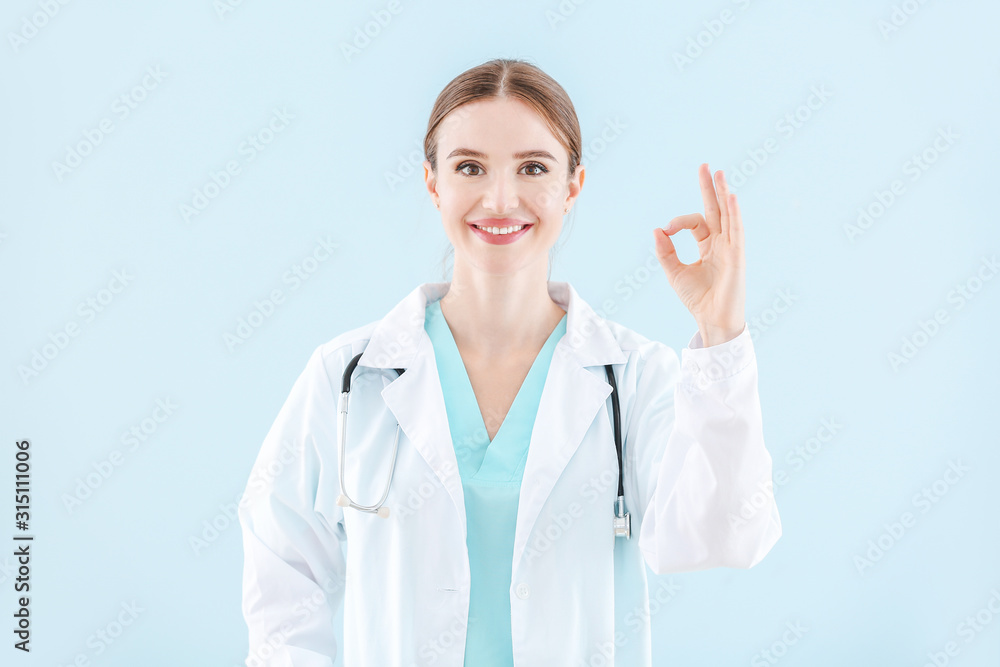Portrait of female doctor showing OK gesture on light background Portrait of female doctor showing OK gesture on light background