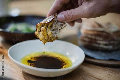 Close up hand dipping bread in olive oil and balsamic vinegar photo