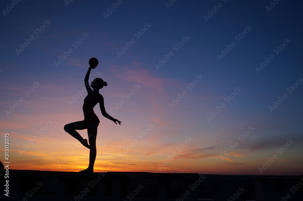 dancer in the dance does the splits in the air against the sunset