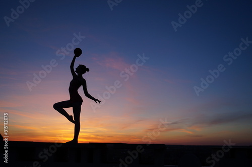 dancer in the dance does the splits in the air against the sunset