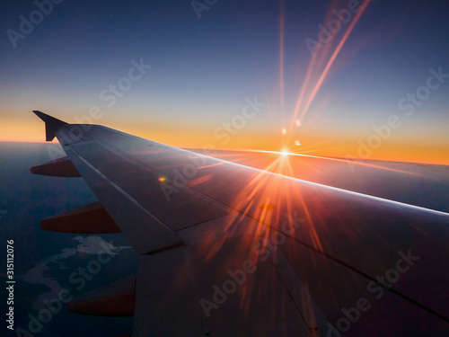 Sunset behind airplane wing in sky