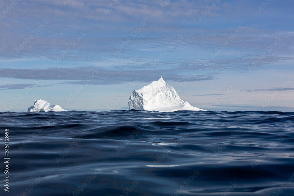 Majestic iceberg formations over sunny blue ocean Majestic iceberg formations over sunny blue ocean