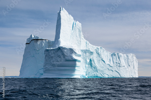 Majestic towering iceberg on sunny blue Atlantic Ocean Greenland