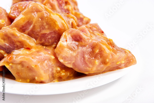 raw meat marinated in spicy sauce close-up, isolated on white background with slices pepper © draw05