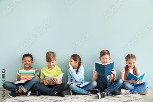 Cute little children reading books on color background photo
