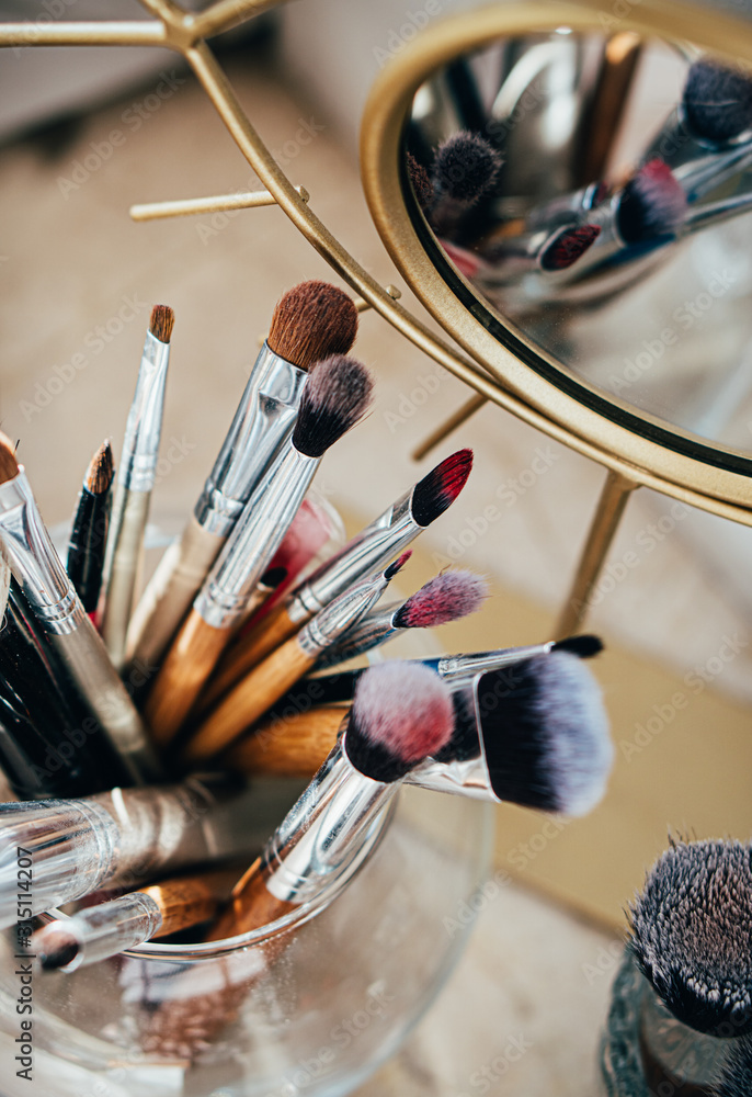 Many different makeup brushes in artist's studio with mirror reflection - obrazy, fototapety, plakaty 
