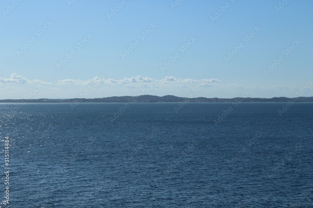 blue sea with mountain silhouettes on horizon and infinite blue sky