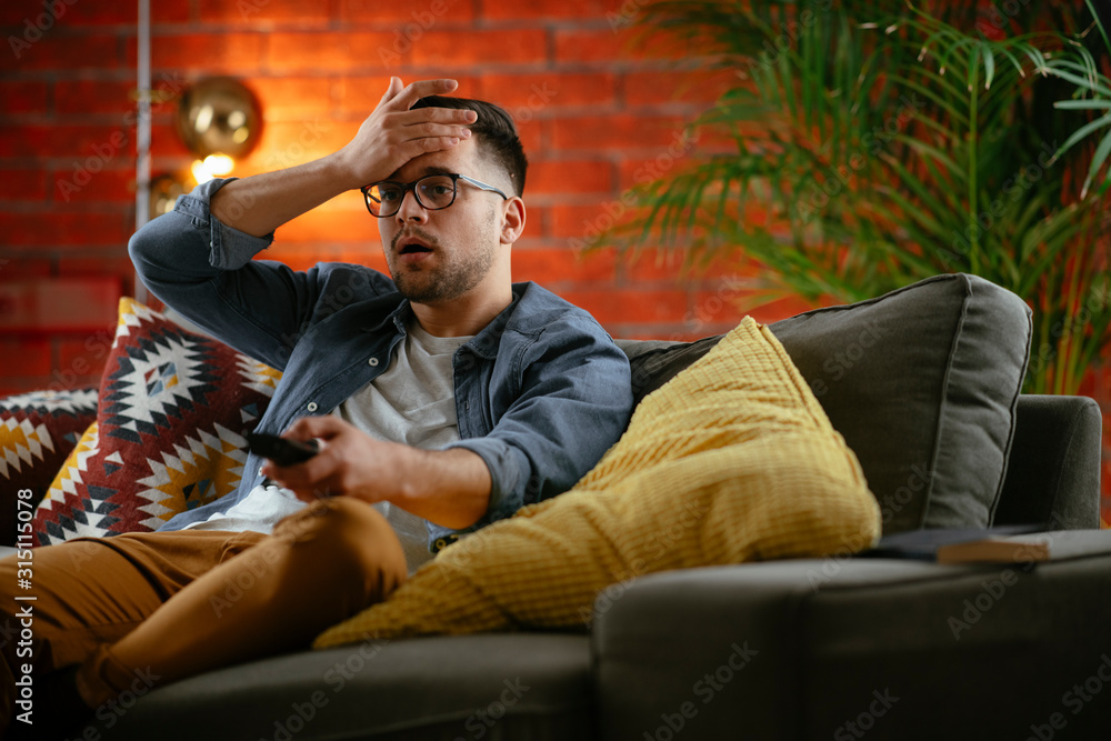 Fototapeta premium Young man watching tv at home. 