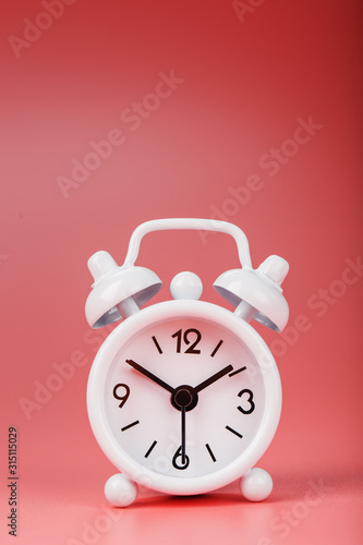 White retro alarm clock on pink background. Concept of time with free space for text.
