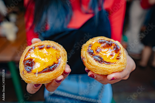 Photography An egg tart placed on the hand of a woman in Macau