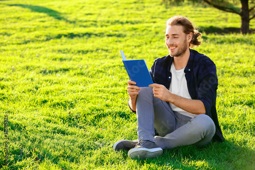 Handsome man reading book outdoors