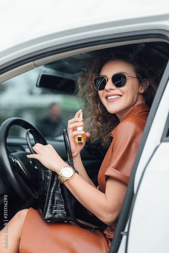 Naklejka premium Living in a business world. Portarit of businesswoman using her perfume in the car.