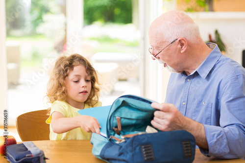 Grandfather and grandson are packing a backpack for school