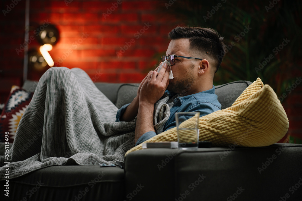Fototapeta premium Young sick man sitting on sofa.