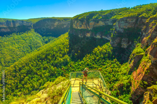 Tourist backpacker at balcony looks panoramic views at Pulpit Rock in Blue Mountains National Park, New South Wales, Australia. Australian landscape of Grose Valley, Blue Gum Forest and Govetts Leap. photo