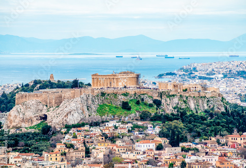 View of the Acropolis of Athens (in Greece) with Filopappos Hill, the Saronic gulf and the port of Piraeus in the background.