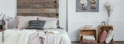 Panoramic view of trendy bedroom in rustic style with wooden boxes as nightstand tables