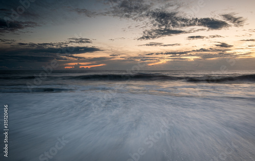 Seawaves splashing on the coast during a dramatic sunset