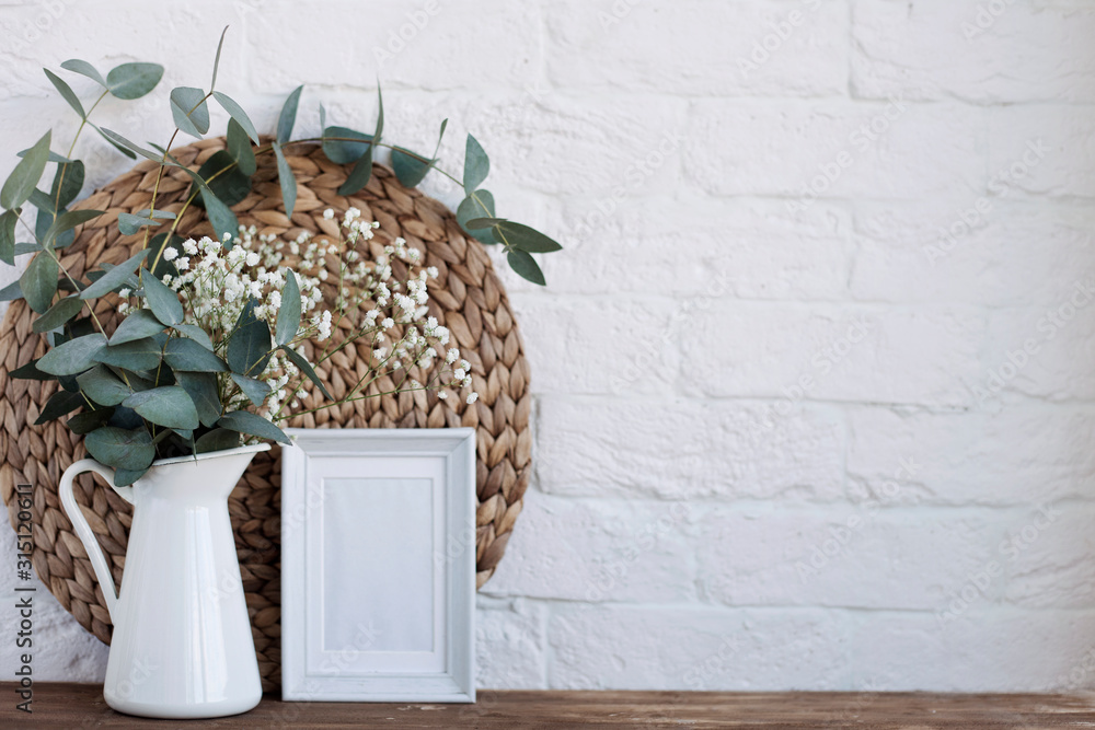 Obraz premium vase with flowers and a photo frame at home on a wooden table.