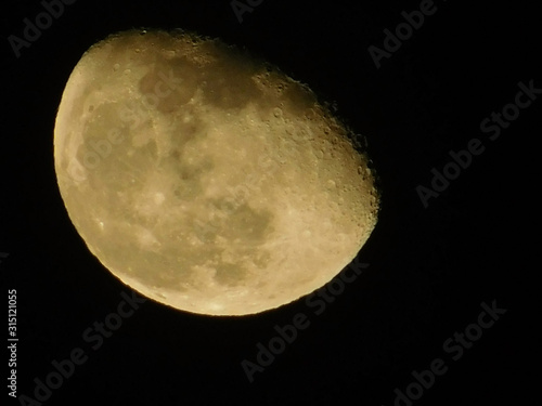 Half moon rising beige moon in the black night sky close up