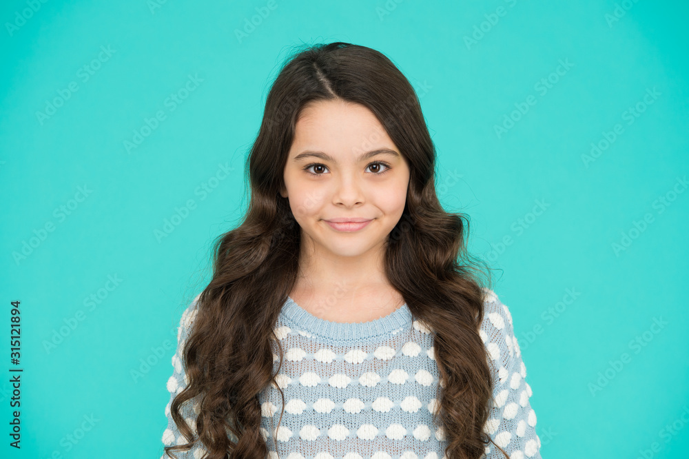 She is really cute. Happy girl child blue background. Small child wear long wavy hair. Little child with cute smile. Beauty salon. Fashion and style. Child care and childhood She is really cute. Happy girl child blue background. Small child wear long wavy hair. Little child with cute smile. Beauty salon. Fashion and style. Child care and childhood