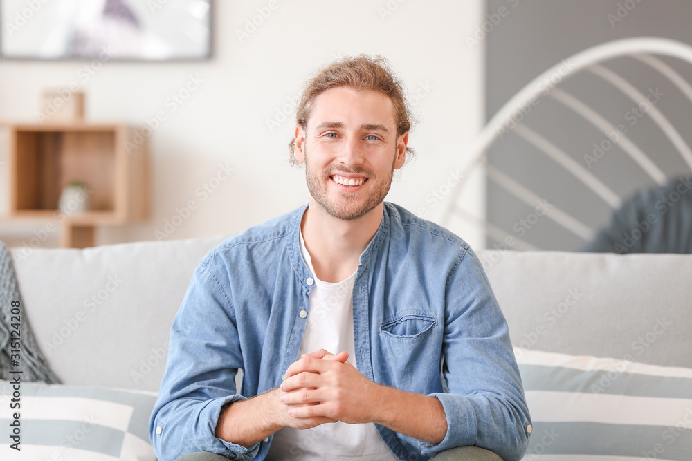 Handsome man sitting on sofa at home Handsome man sitting on sofa at home