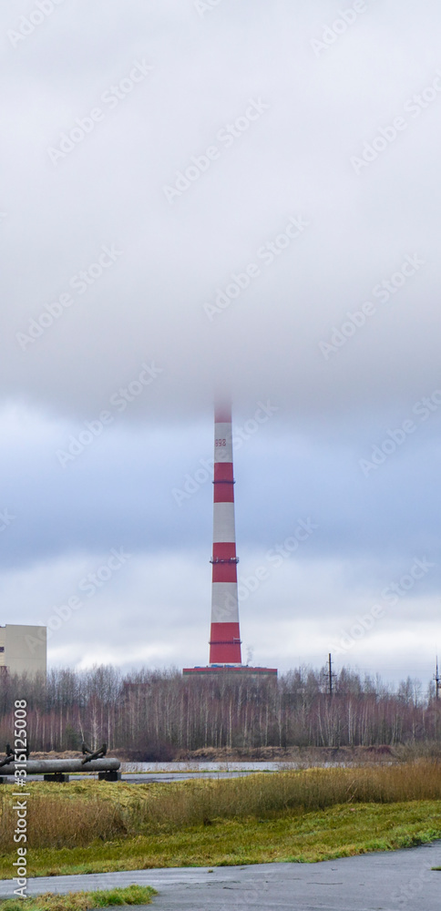 Red-white factory chimney near a winter lake. Red-white factory chimney near a winter lake.
