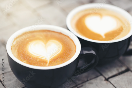 Two black mugs with a coffee drawn in a heart shape.
