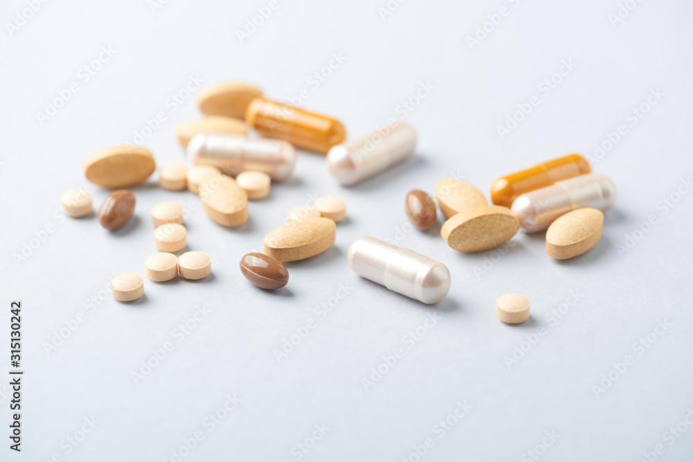 Multicolor vitamins and supplements on bright paper background. Concept for a healthy dietary supplementation. Close up. Multicolor vitamins and supplements on bright paper background. Concept for a healthy dietary supplementation. Close up.