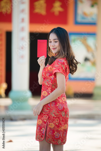 Portrait of beautiful asian woman in Cheongsam dress,Thailand people,Happy Chinese new year concept,Holding red envelope red.