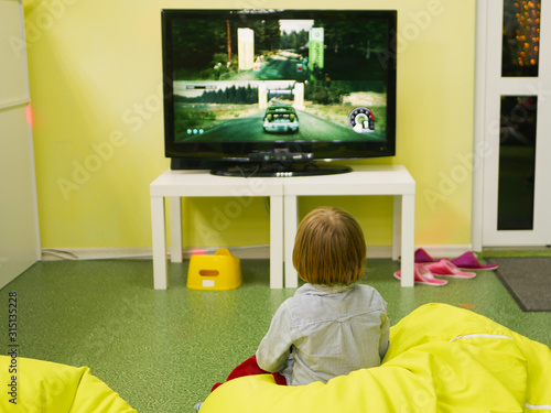 A child plays a game console alone. plays video games.