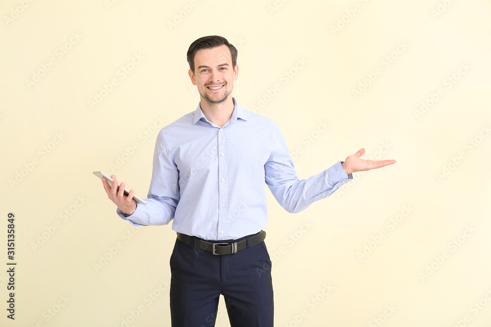 Male real estate agent with tablet computer showing something on light background Male real estate agent with tablet computer showing something on light background