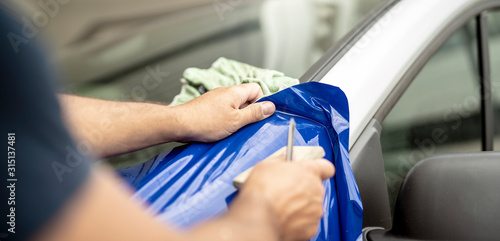 Werbetechniker foliert ein Auto mit blauer Folie	 photo