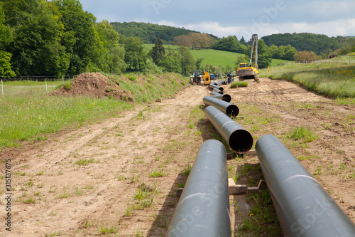 Various unplugged gas pipes lead in an idyllic landscape to the background with equippment to pipe laying photo