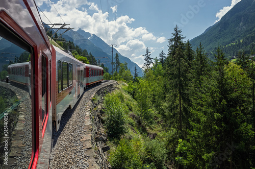 The train follows the route in the mountains on a sunny day. Swiss Alps. Zermatt.