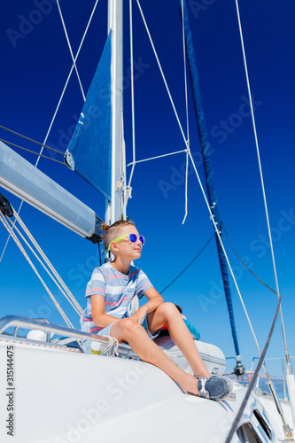 Little boy on board of sailing yacht on summer cruise. Travel adventure, yachting with child on family vacation. photo