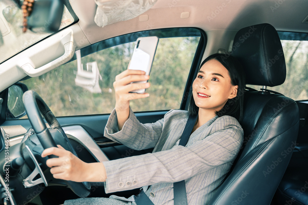 Asian woman talk by mobile calling texting and looking on a cellular phone while sitting in her car, driving under the influence, the driver is safely talking by smartphone in a car concept