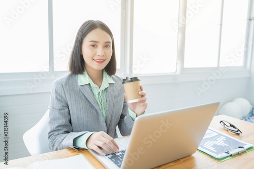 Asian young business women working with new project laptop drinking coffee in coffee shop cafe  Analyze plans  papers  hands texting keyboard. design notebook technology or startup business concept