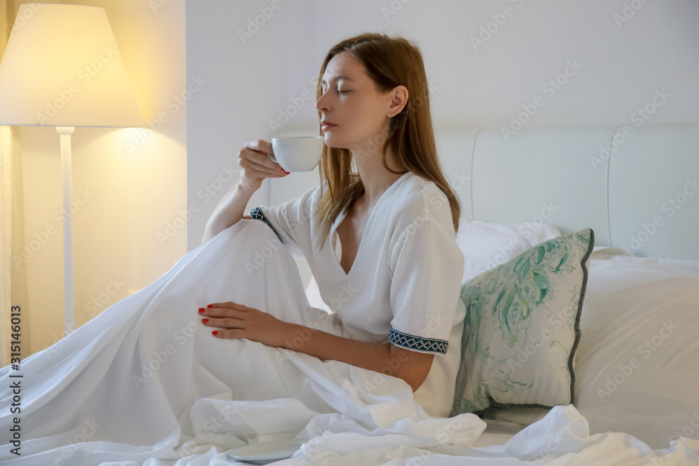 Serene woman drinking coffee in the bed, casual relaxing time alone Serene woman drinking coffee in the bed, casual relaxing time alone