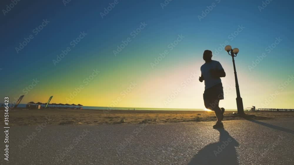 Man running on the beach at sunset, steadicam cinematic shot Man running on the beach at sunset, steadicam cinematic shot