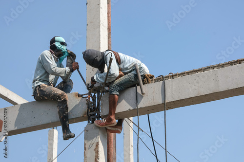 two worker man welding steel concrete pile high house structure in construction site photo