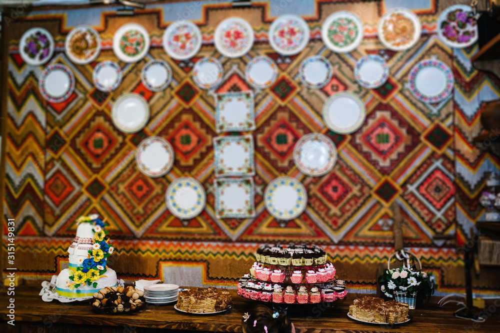 Sweet table. A plates of cakes and muffins. Table with sweets, candy, buffet. Dessert, goodies. Close up. party, decorated in restaurant. candy bar in the Ukrainian style with embroidered vestments.