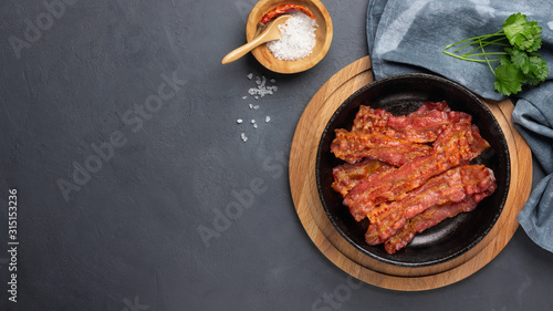 Crispy fried bacon in a cast iron pan on a gray background. photo