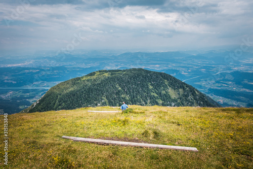 Summit of mountain Hochobir with man on bench, Carinthia, Austria photo
