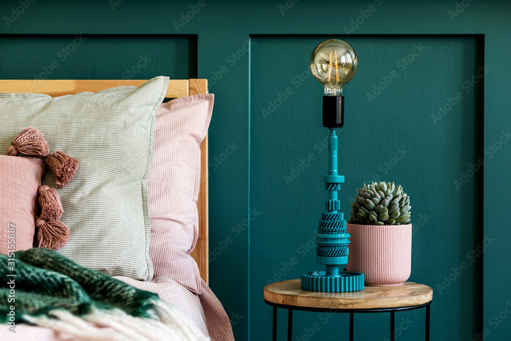 Stylish home interior of bedroom with design coffee table, table lamp, succulent and beautiful plant. Green wall panelling. Beautiful bed sheets, blanket and pillow. Template. Home staging.  - obrazy, fototapety, plakaty 