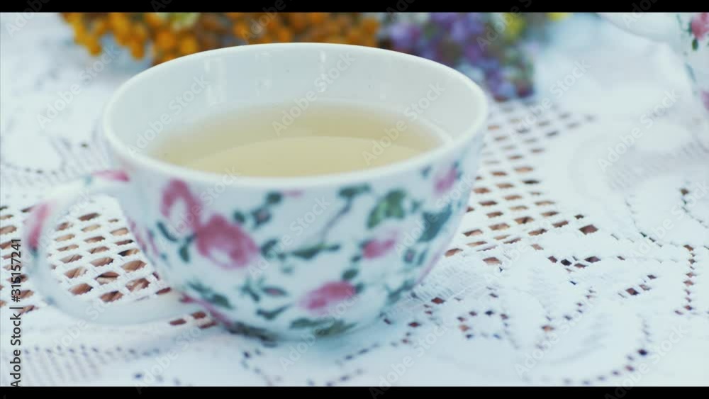 Сup of fragrant tea, wildflowers on a snow-white tablecloth in nature Сup of fragrant tea, wildflowers on a snow-white tablecloth in nature