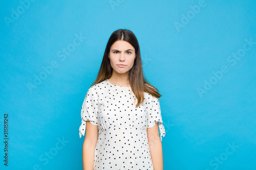 young pretty woman feeling sad and whiney with an unhappy look, crying with a negative and frustrated attitude against blue wall photo