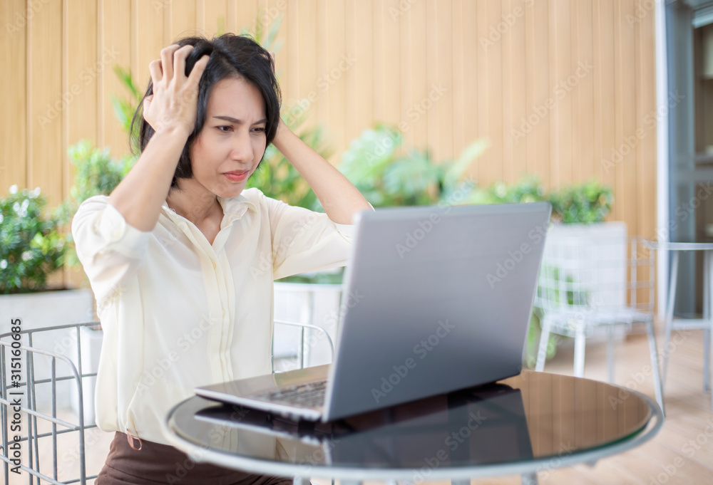 Beautiful Asian self employed or freelance business woman having stress while working with her laptop at the restaurant terrace Beautiful Asian self employed or freelance business woman having stress while working with her laptop at the restaurant terrace